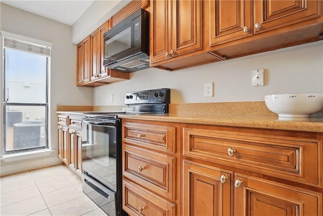 kitchen featuring black appliances, brown cabinets, light tile patterned floors, and light stone counters