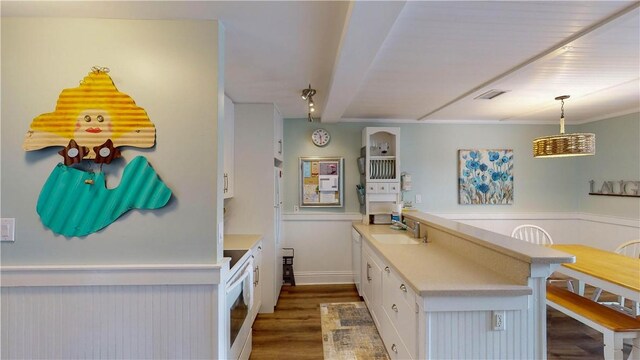 kitchen with dark wood-type flooring, a sink, white cabinetry, light countertops, and hanging light fixtures