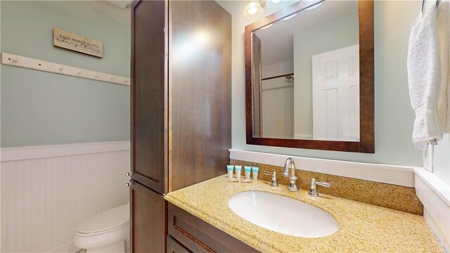 bathroom with toilet, a wainscoted wall, and vanity