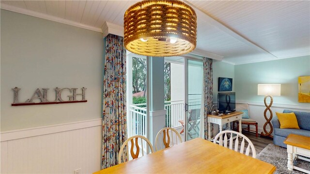 dining area with ornamental molding, a wainscoted wall, and wood finished floors