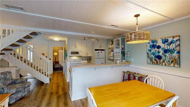 kitchen featuring a peninsula, white appliances, visible vents, white cabinetry, and light countertops