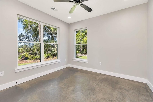 empty room featuring ceiling fan, plenty of natural light, and concrete flooring