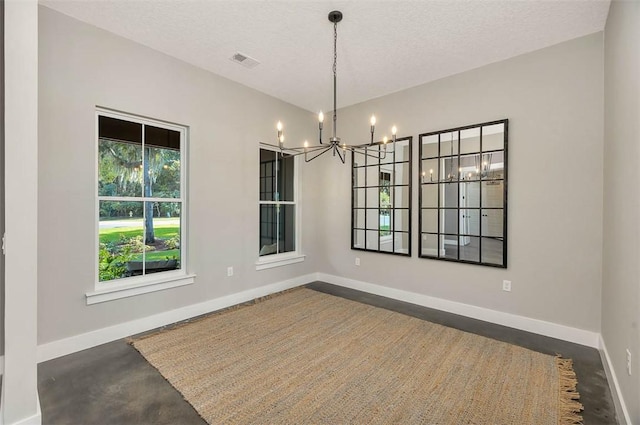 unfurnished dining area with a chandelier and a textured ceiling