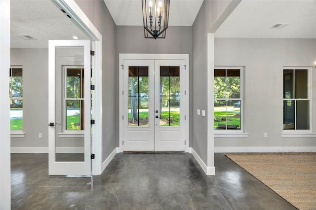 foyer featuring an inviting chandelier, a textured ceiling, and french doors