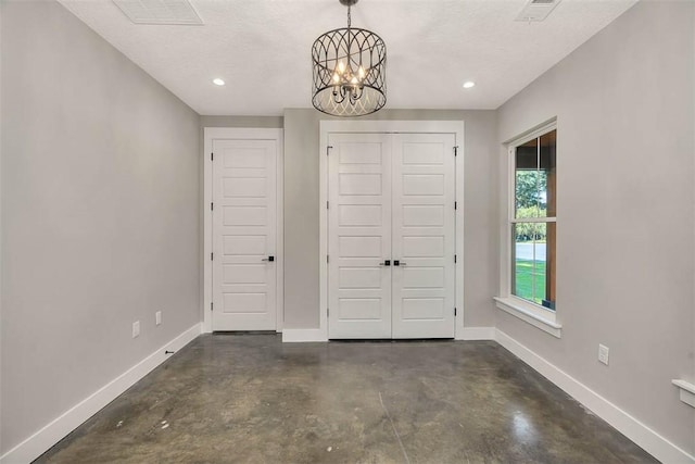 unfurnished bedroom with a notable chandelier, a textured ceiling, and a closet