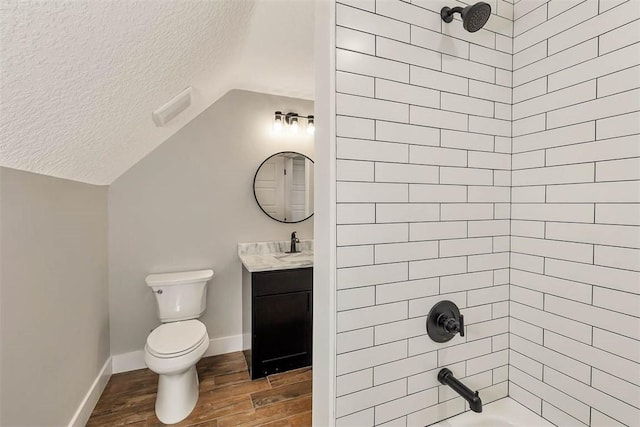 full bathroom with vanity, tiled shower / bath, vaulted ceiling, hardwood / wood-style flooring, and a textured ceiling