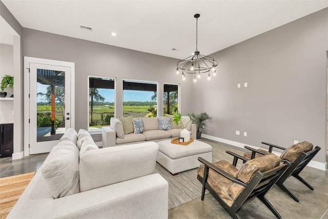 living room with concrete flooring, an inviting chandelier, and a wealth of natural light