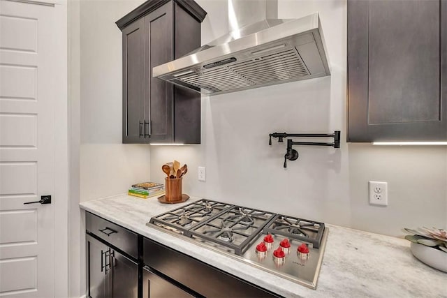 kitchen with dark brown cabinetry, wall chimney range hood, and stainless steel gas cooktop