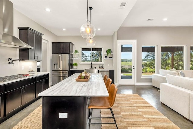 kitchen with plenty of natural light, a center island, wall chimney range hood, and stainless steel appliances