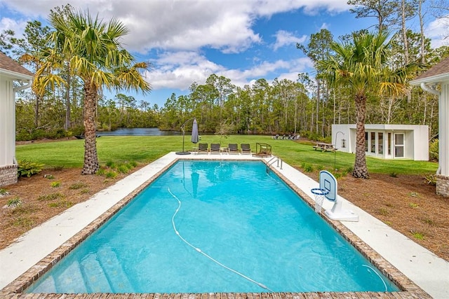 view of swimming pool with a yard, a water view, and an outdoor structure