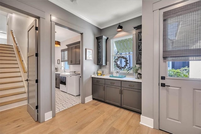 interior space featuring washer and clothes dryer, sink, light wood-type flooring, and crown molding