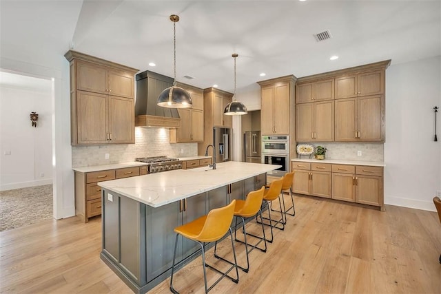 kitchen with a spacious island, light wood-type flooring, a breakfast bar, custom exhaust hood, and appliances with stainless steel finishes