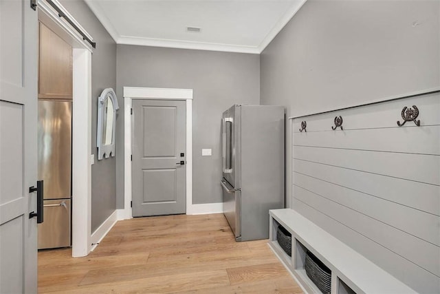 mudroom featuring a barn door, light wood-type flooring, and ornamental molding