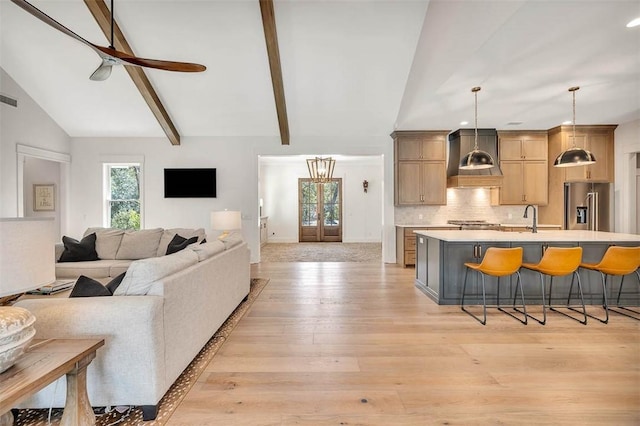 living room with light wood-type flooring, lofted ceiling with beams, ceiling fan, and sink