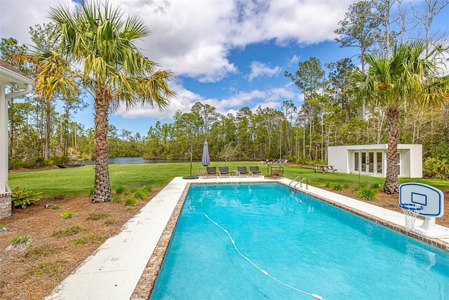 view of pool featuring a lawn, an outbuilding, and a water view