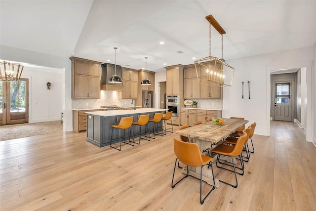 dining space with light wood-type flooring, a notable chandelier, a healthy amount of sunlight, and sink