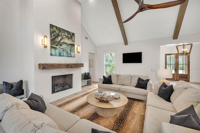 living room featuring beamed ceiling, high vaulted ceiling, a wealth of natural light, and french doors