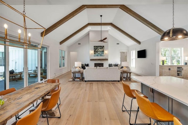 dining area featuring beamed ceiling, high vaulted ceiling, light hardwood / wood-style flooring, and ceiling fan