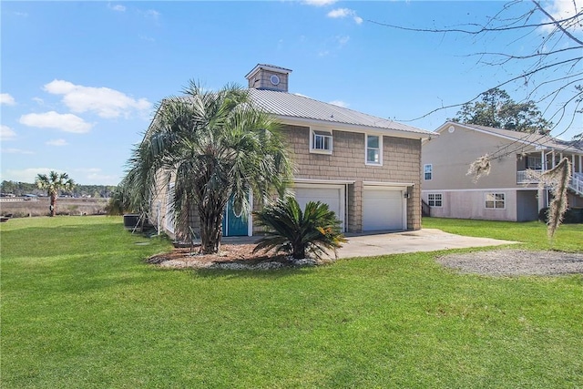 rear view of house featuring metal roof, driveway, a lawn, and an attached garage