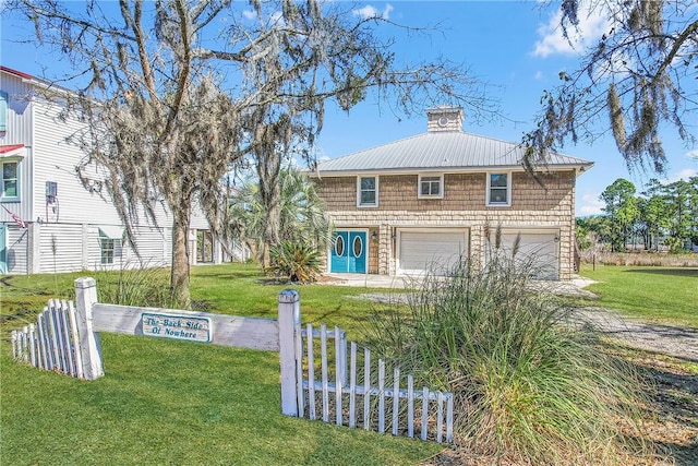 view of front facade featuring a chimney, metal roof, fence, a garage, and a front lawn