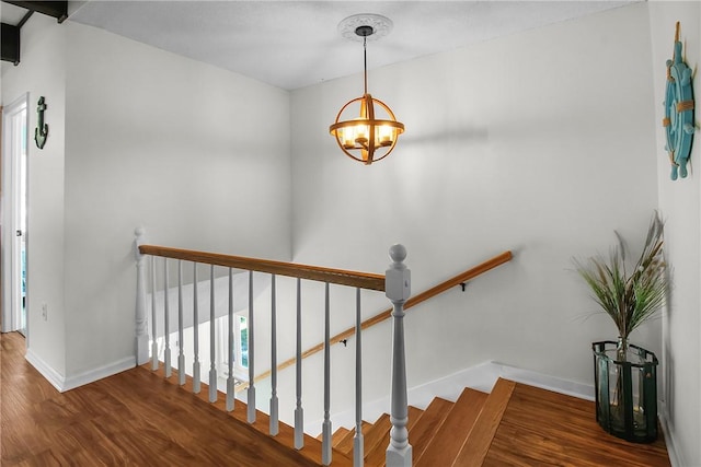 stairs with a notable chandelier, baseboards, and wood finished floors