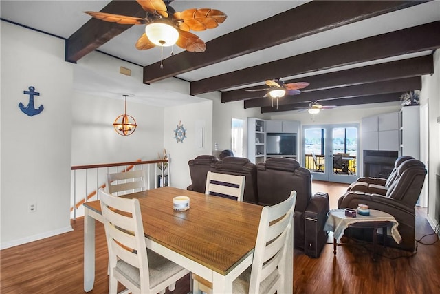 dining space featuring ceiling fan with notable chandelier, beam ceiling, baseboards, and wood finished floors