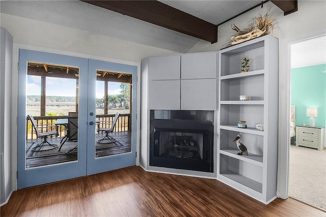 unfurnished living room featuring built in shelves, french doors, dark wood-style flooring, a fireplace, and beamed ceiling