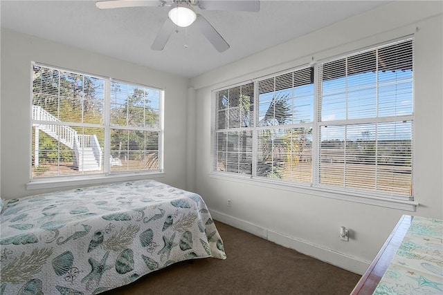 bedroom with baseboards, dark colored carpet, and a ceiling fan