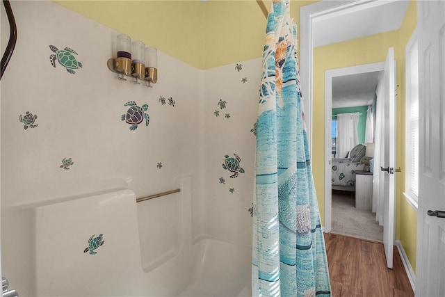 bathroom with curtained shower, ensuite bath, baseboards, and wood finished floors