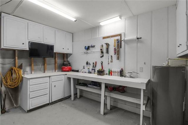 interior space featuring water heater, light countertops, unfinished concrete flooring, and white cabinets