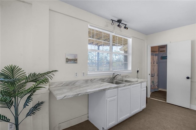 kitchen featuring light carpet, a sink, and white cabinetry