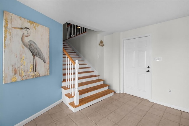 entrance foyer featuring stairway, light tile patterned flooring, and baseboards