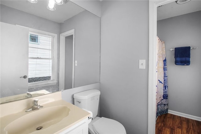 bathroom featuring toilet, baseboards, wood finished floors, and vanity