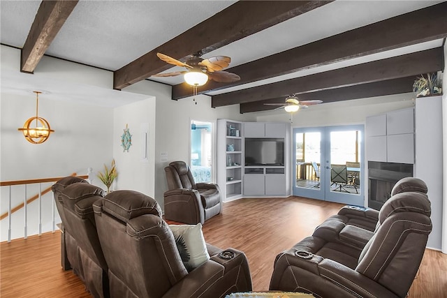 living area featuring light wood-type flooring, french doors, beam ceiling, and ceiling fan with notable chandelier