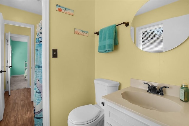 full bath with toilet, wood finished floors, and vanity