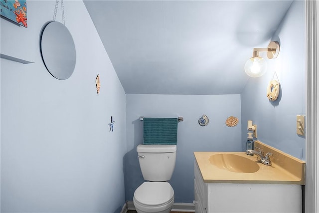 bathroom with toilet, vaulted ceiling, and vanity