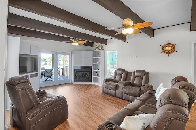 living area with light wood-style floors, ceiling fan, beamed ceiling, and french doors