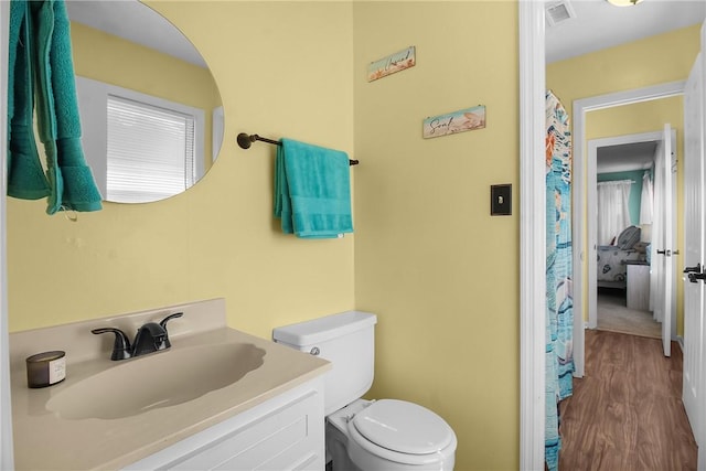 bathroom with visible vents, toilet, wood finished floors, and vanity