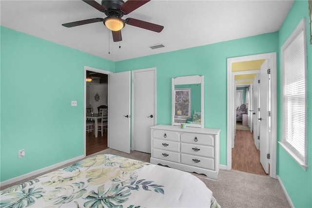 bedroom with ceiling fan, light colored carpet, visible vents, baseboards, and a closet