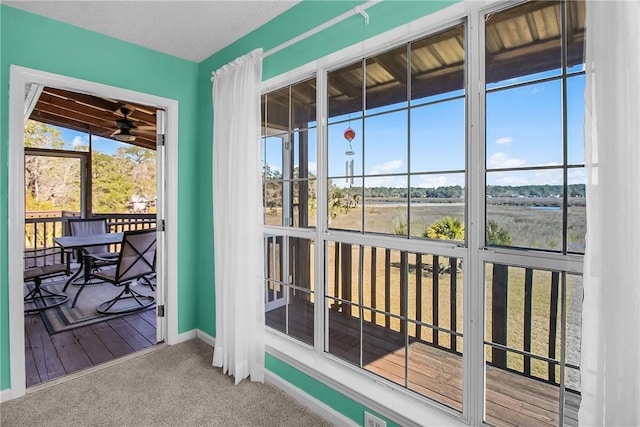 doorway to outside with carpet, a textured ceiling, and baseboards