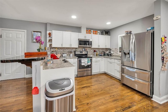 kitchen featuring sink, stainless steel appliances, kitchen peninsula, light hardwood / wood-style floors, and white cabinets