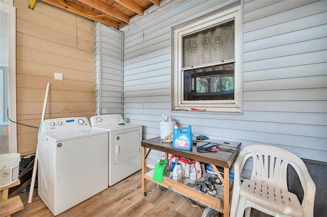 laundry area featuring washing machine and dryer, wood walls, and light hardwood / wood-style floors