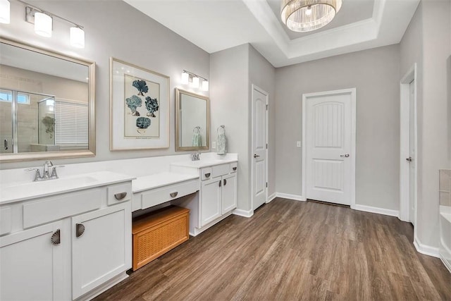 bathroom featuring a chandelier, wood-type flooring, a raised ceiling, and vanity