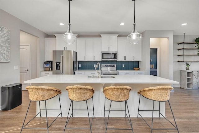 kitchen featuring white cabinetry, appliances with stainless steel finishes, sink, and a center island with sink