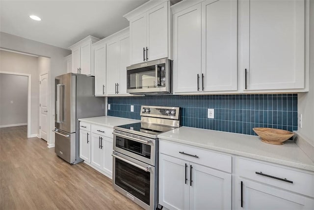 kitchen featuring white cabinetry, light wood-type flooring, tasteful backsplash, and appliances with stainless steel finishes