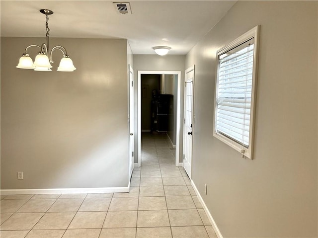 corridor featuring light tile patterned floors and a notable chandelier