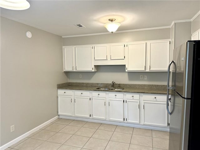 kitchen featuring light tile patterned floors, sink, white cabinetry, and stainless steel fridge