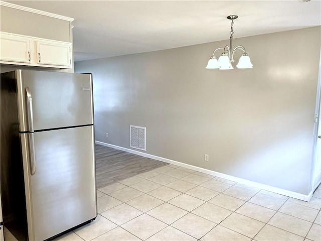 kitchen with white cabinets, hanging light fixtures, stainless steel fridge, a notable chandelier, and light tile patterned floors