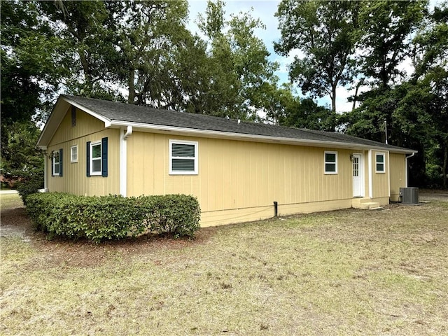 view of side of home featuring cooling unit and a lawn
