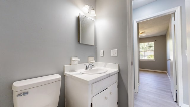 1301 Riverside Ave, Waycross, GA 31501 - half bath with wood finished floors, toilet, vanity, baseboards, and ceiling fan